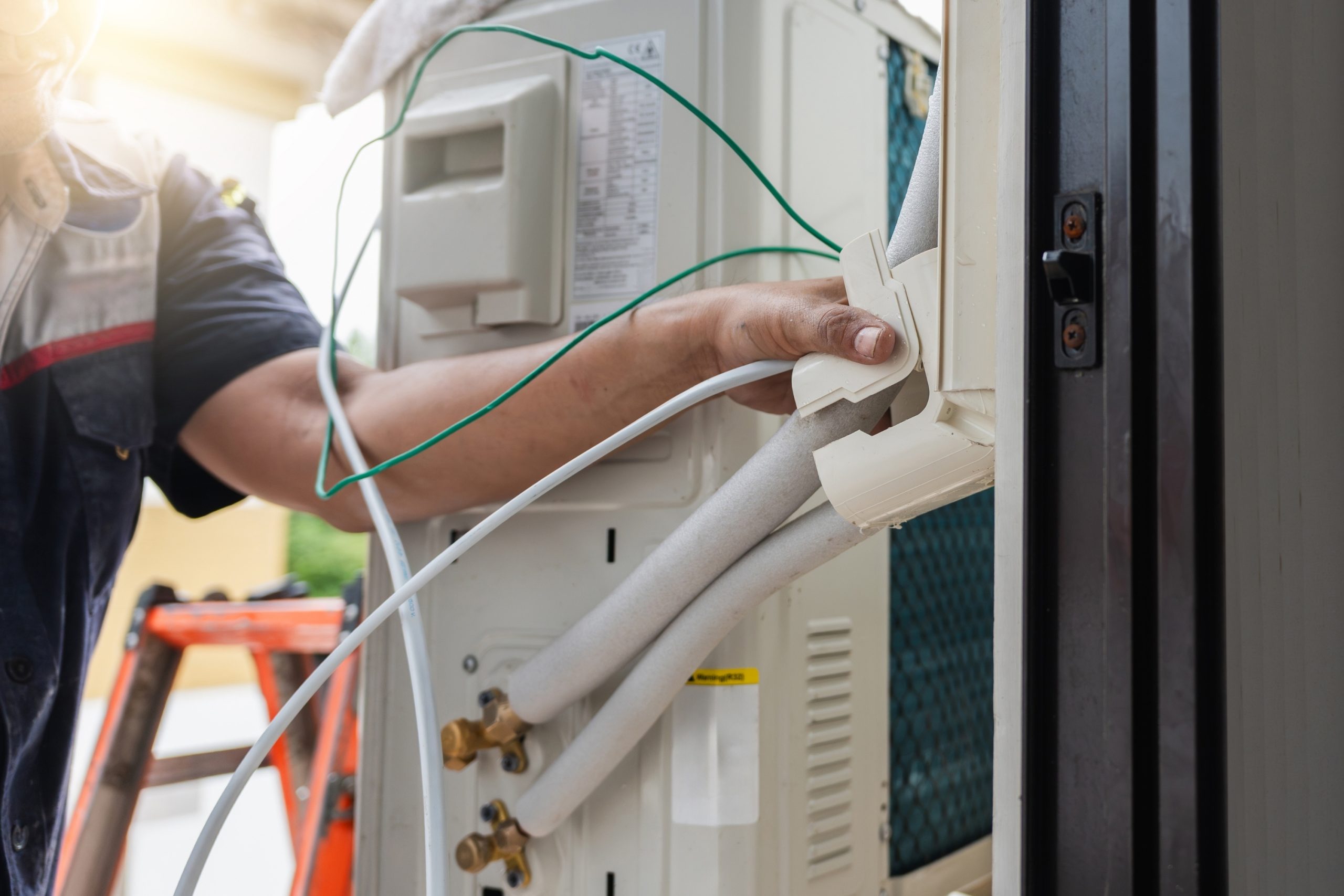Technician routing refrigerant line set and wiring into an outdoor unit