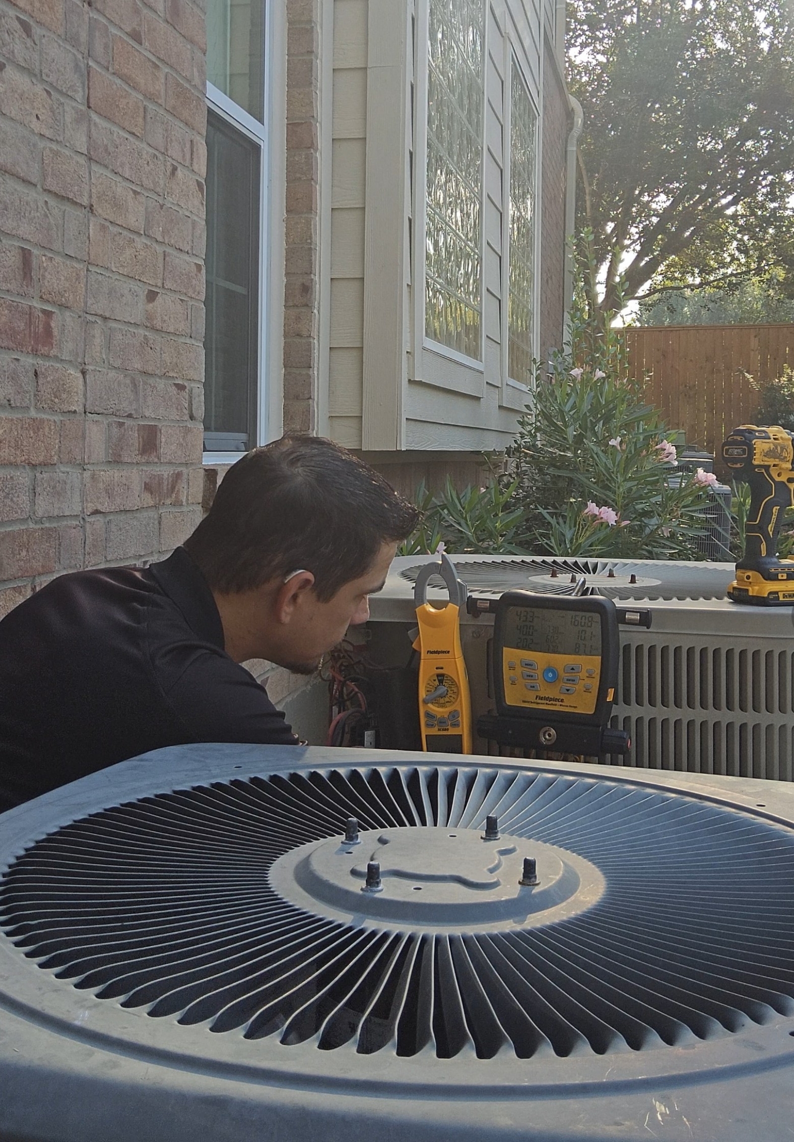 HVAC technician servicing the fan assembly of a residential air conditioner